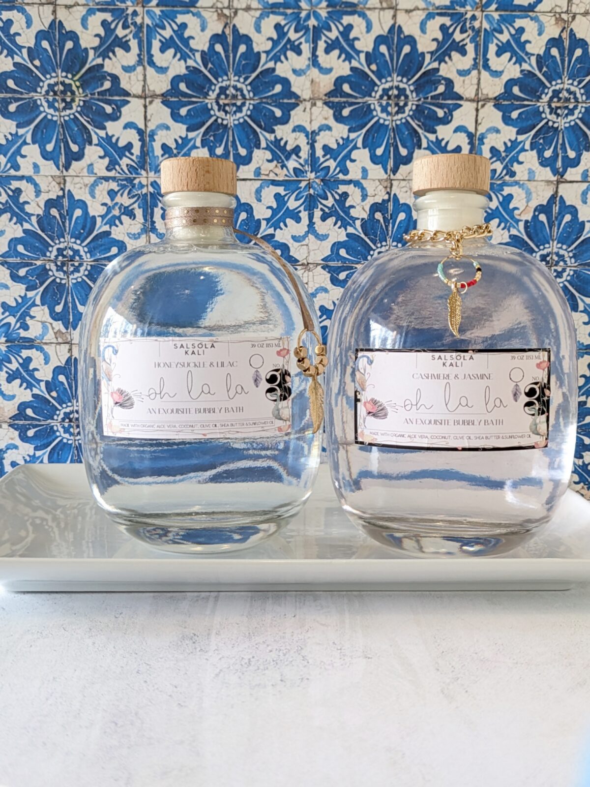 Large, unique round glass bottle of Cashmere & Jasmine scented luxury bubbly bath with a gold leaf charm.