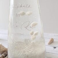 The stunning interior of the Abyss bottle with sand and floating butter embers for an immersive ocean bath experience.