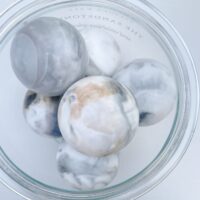 Salsola Kali Nero Sand Strata layered soap spheres in a luxury apothecary jar.